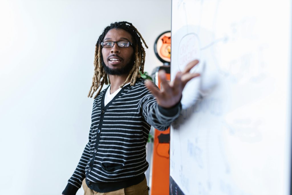 Young man with dreadlocks giving a presentation in a modern office environment.