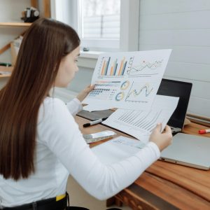 Woman reviewing business charts in a home office setting, showcasing remote work lifestyle.